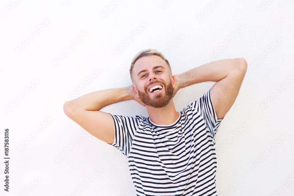 young man laughing with hands behind head young man laughing with hands behind head