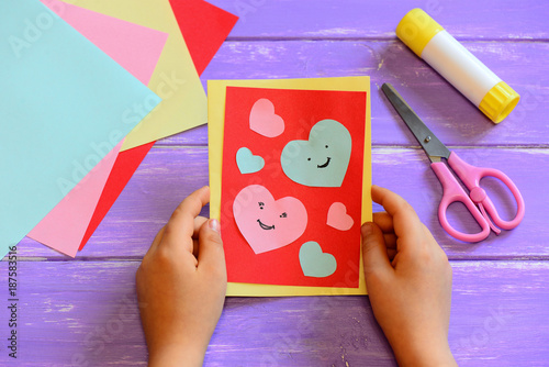 Child is holding a Valentines day card in his hands. Small child made a Valentines day greeting card. Cute and simple paper crafts for kindergarten. Closeup