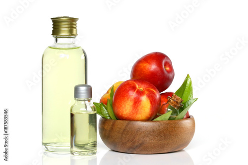 Peach natural organic oil. Peach oil in a glass bottle and ripe peaches in a wooden cup. 