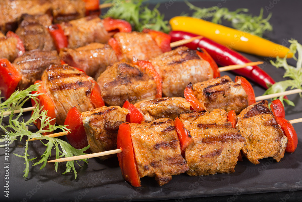 shish kebab from meat on a black slate, sticks of pepper and spices