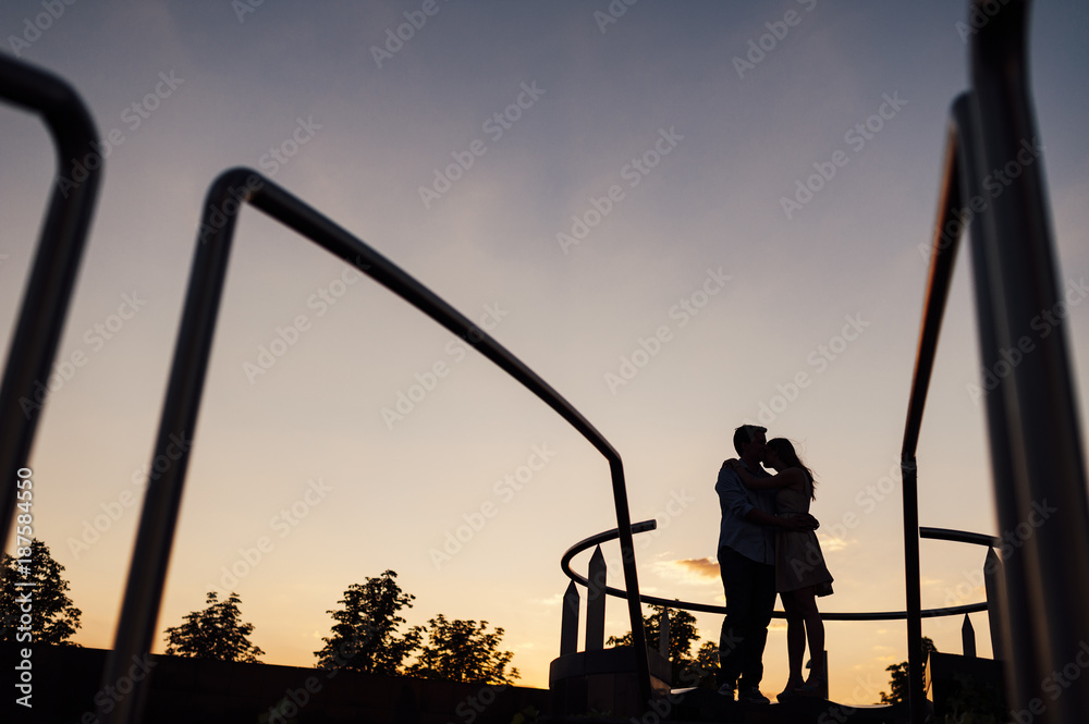 Silhouette of a couple hugging close to a circular staircase at dusk Silhouette of a couple hugging close to a circular staircase at dusk