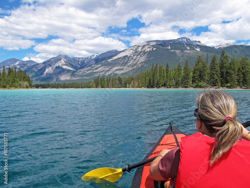 Woman kayaking with red inflatable kayak on turquoise colored Edith Lake, Jasper, Rocky Mountains, Canada