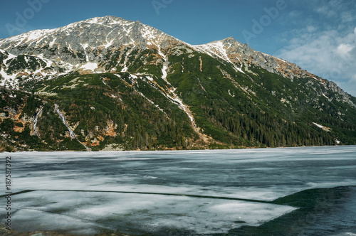 view of snowscaped mountain hill and lake with ice, Morskie Oko, Sea Eye, Tatra National Park, Poland photo