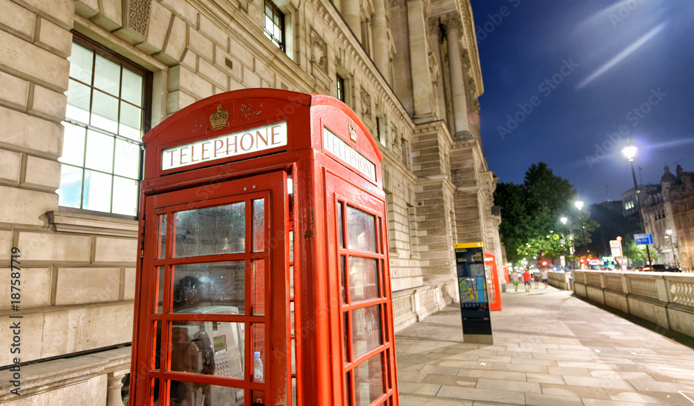 Red public phone booth in London at night near Westminster, UK