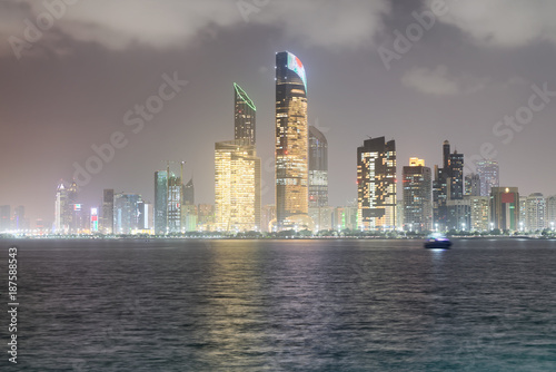 ABU DHABI  UAE - DECEMBER 8  2016  Reflections of Corniche Road buildings at night as seen from Marina. The city attracts 10 million tourists annually