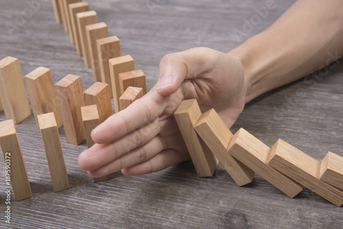 hand stopping wooden block domino. concept prevent and solution. photo