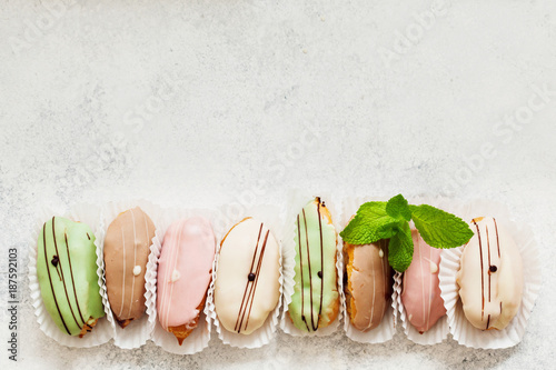 Top view of cute mini eclair cakes in pastel colors garnished with mint and served with champagne photo