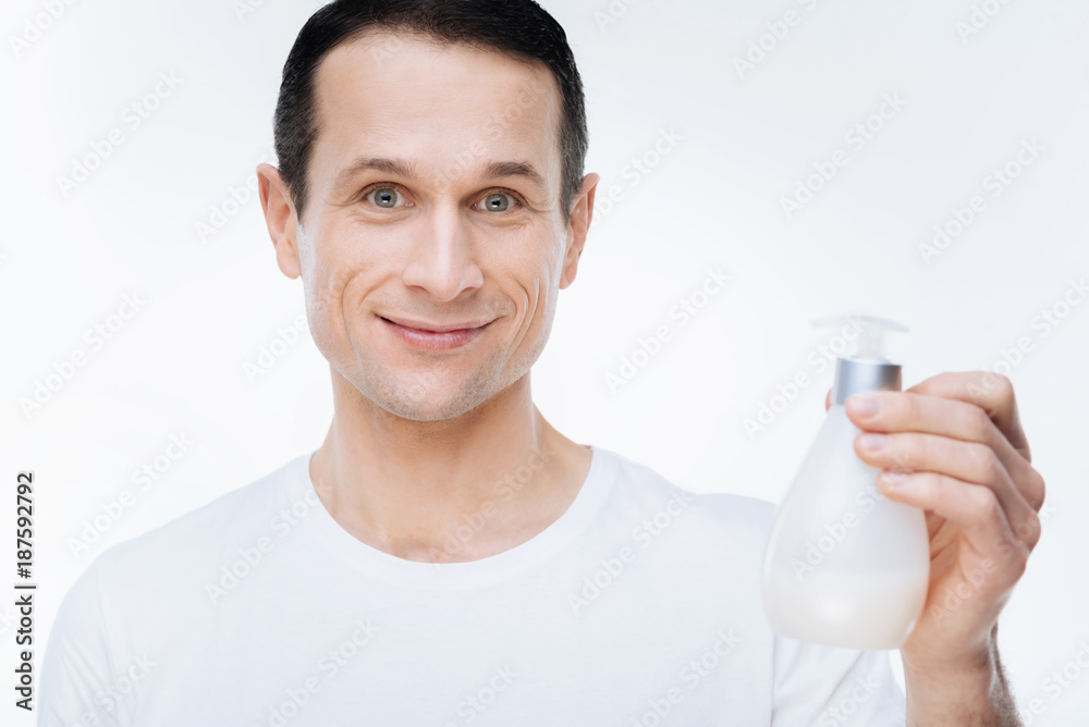 Clean hands. Portrait of a nice delighted man smiling and holding soap while cleaning his hands Clean hands. Portrait of a nice delighted man smiling and holding soap while cleaning his hands
