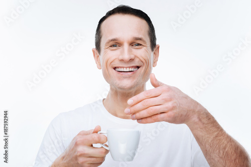 So energizing. Cheerful nice happy man smiling and looking at you while enjoying the coffee smell