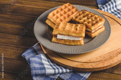 waffles with cream on plate on wooden table.