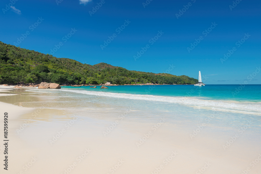 Paradise Anse Lazio beach at Praslin island and sailboat on horizon, Seychelles.
