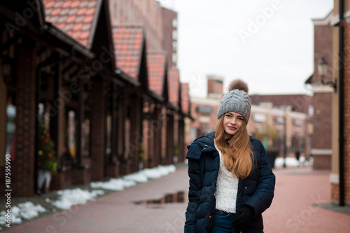 Cool blonde woman wearing black winter coat and knitted hat posing at the street in Kiev
