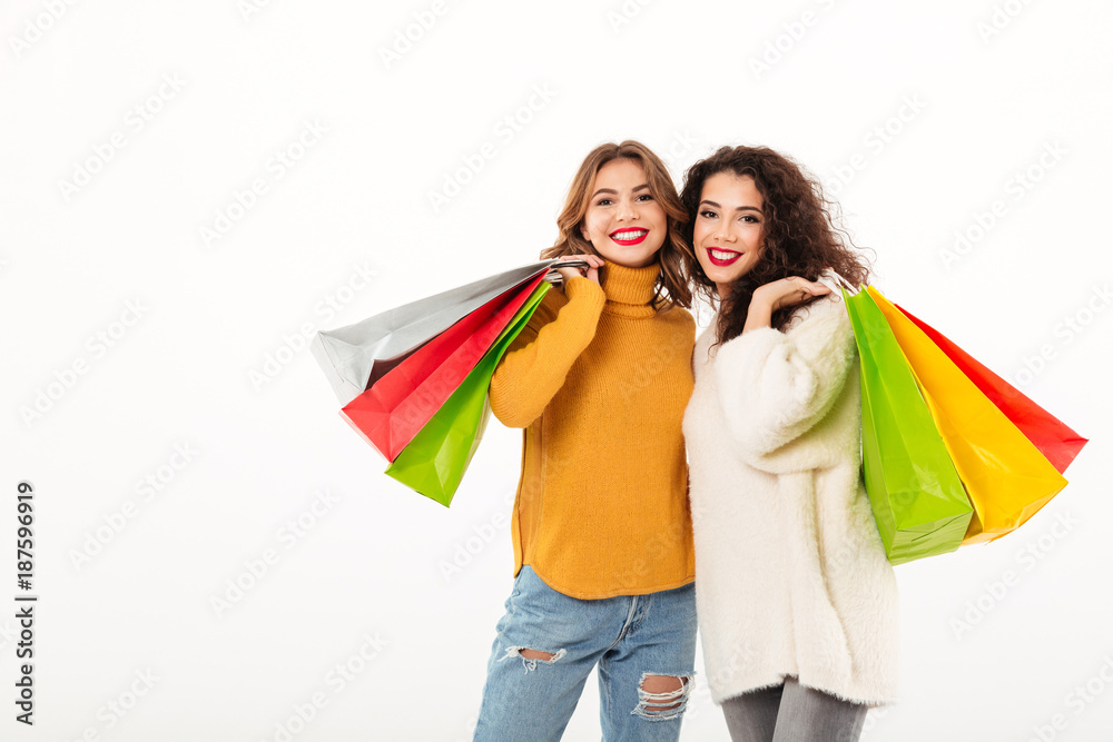 Two happy girls in sweaters with packages looking at camera