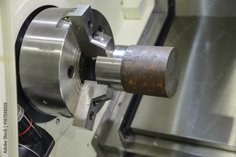 The CNC lathe machine cutting the steel rod .The raw material bar clmaping on the CNC lathe machine The CNC lathe machine cutting the steel rod .The raw material bar clmaping on the CNC lathe machine