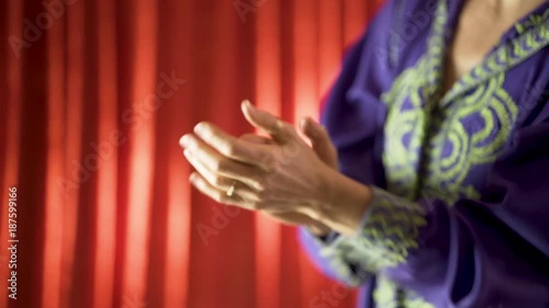 Closeup of woman wearing blue djellaba and rings clapping rhythmically. photo