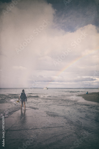 Girl walking on the shore, dramatic sky
