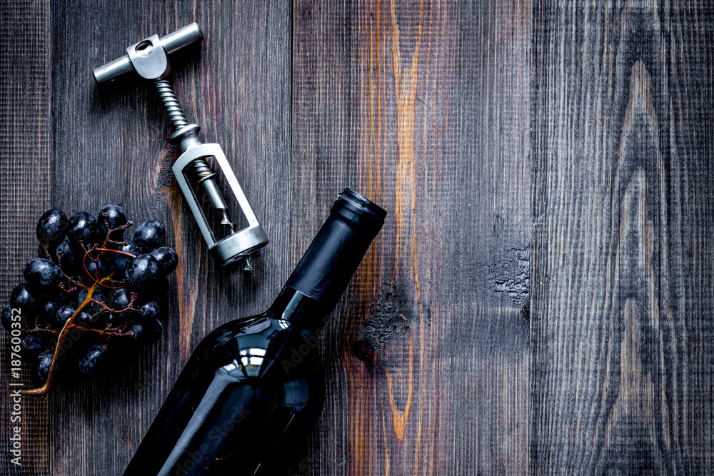 Open wine. Bottle and corkscrew on dark wooden table background 