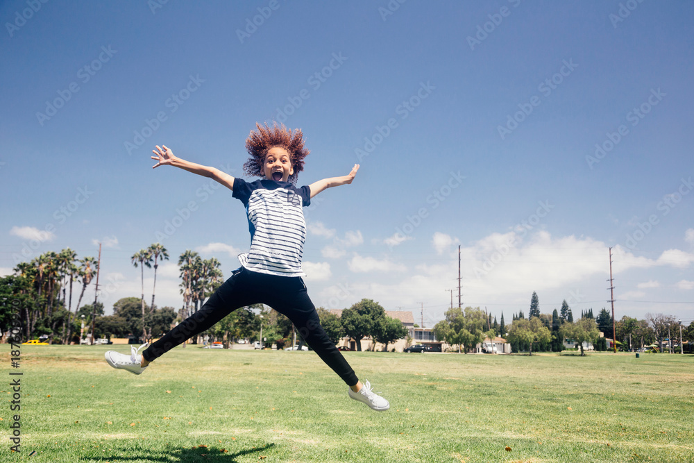 Schoolgirl doing star jump on school sports field Schoolgirl doing star jump on school sports field