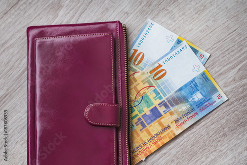 Still life of cash. Bordeaux leather wallet and Swiss francs on a wooden background