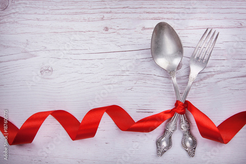 Vintage spoon and fork with a red tape for Valentine's day on a wooden table.