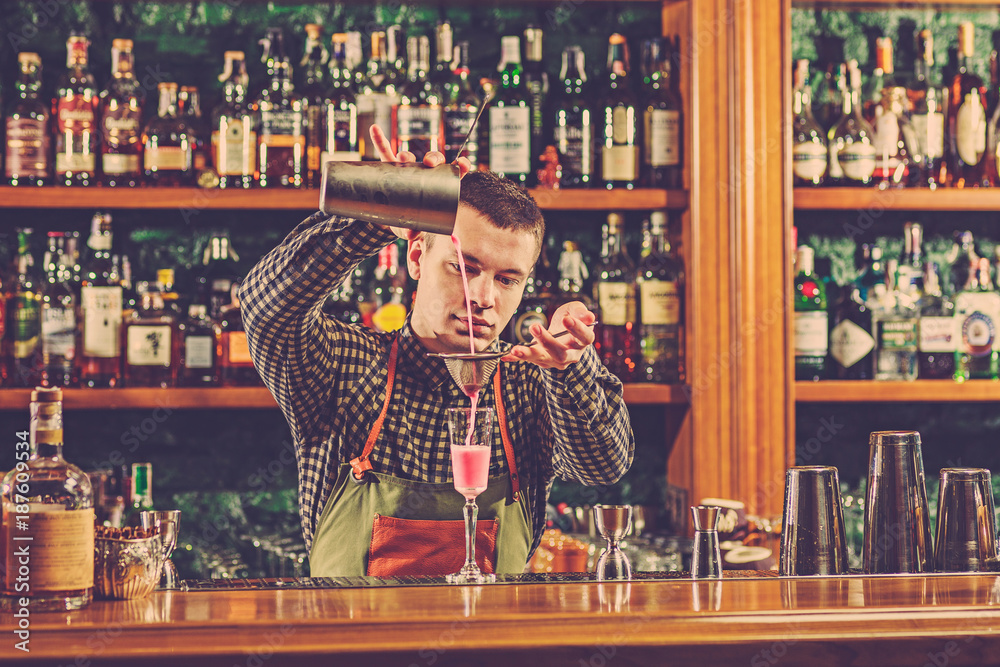 Barman making an alcoholic cocktail at the bar counter on the bar background Barman making an alcoholic cocktail at the bar counter on the bar background