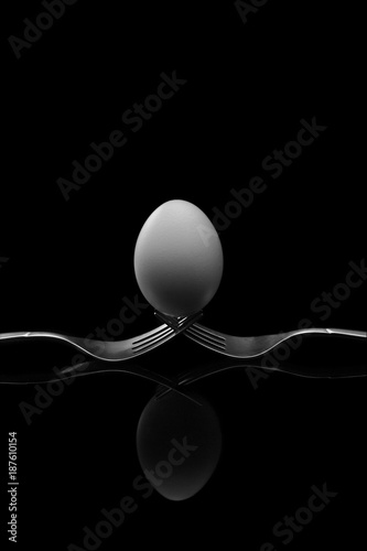 Happy Easter,white egg two forks ancient silver on a black background.