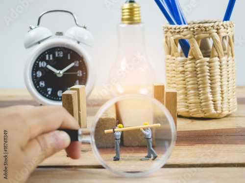Miniature people engineer worker on wood table and white background . Around have a magnifying glass, clock and quare wood.