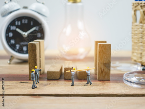 Miniature people engineer worker on wood table and white background . Around have a magnifying glass, clock and quare wood.