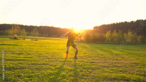 Young athlete doing exercises in beautiful meadow at sunset. Moving the camera. 4K