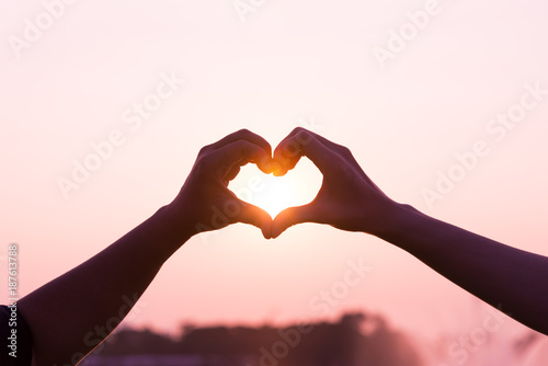 Heart symbol silhouette by woman and man hands together direct to morning pink love sun light with empty copy space over sky for text  wordings  logo insertion or decoration  Valentine s day holiday