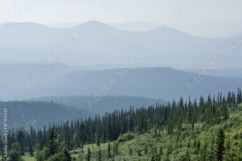Landscape of wooded misty mountains at dawn.