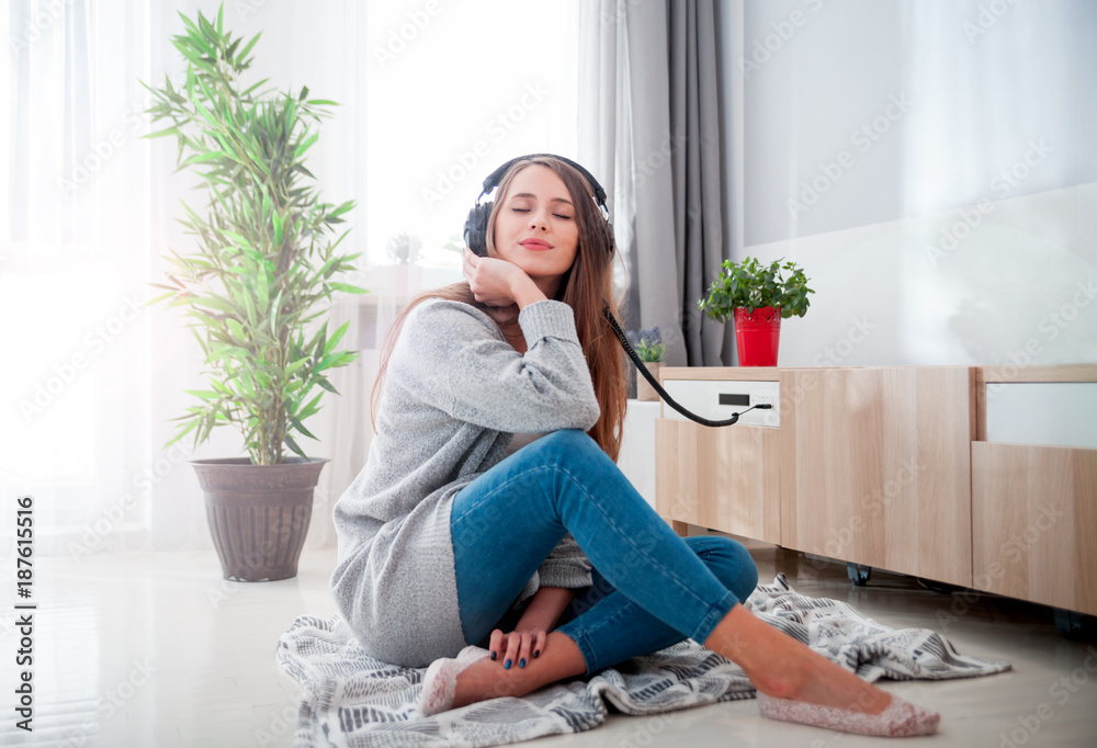 Woman with headphones listening to music at home in living room