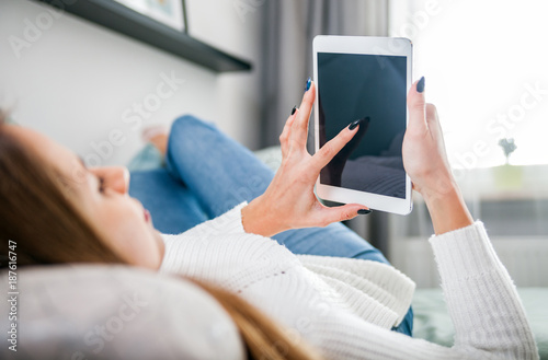 Woman on sofa at home using tablet computer and relaxing