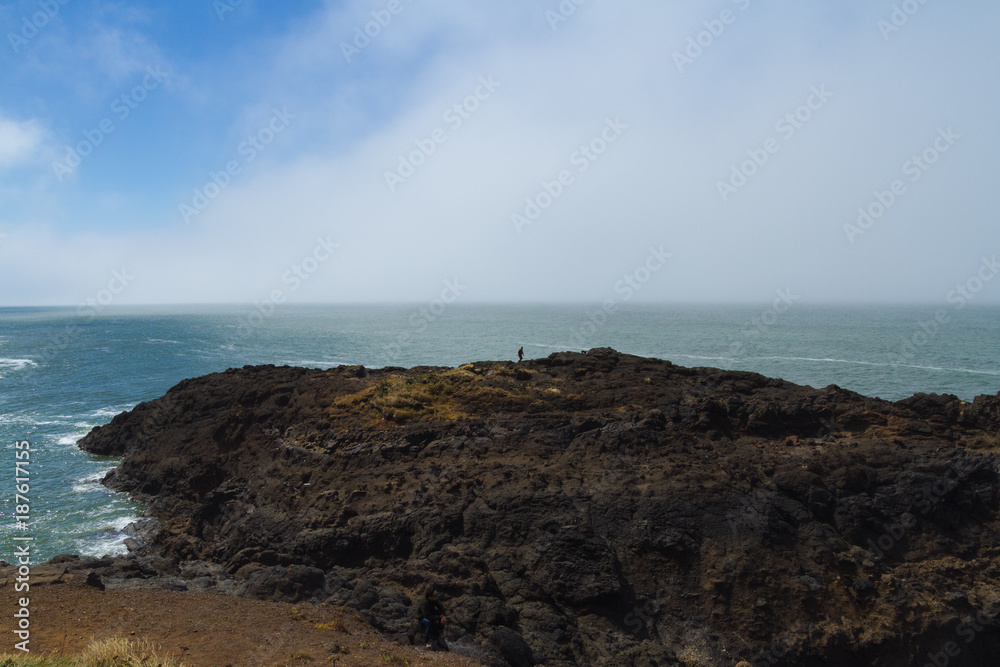 Man standing above coastline covered in fog in Oregon, USA Man standing above coastline covered in fog in Oregon, USA