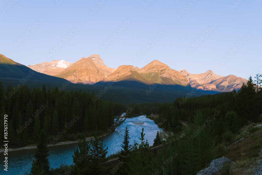 Green river and forest with big mountains in Banff near Lake Louise during sunrise