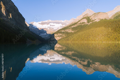 Reflection on Lake Louise in Rocky Mountains in Canada during sunrise on sunny day