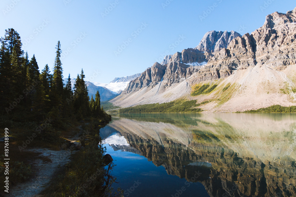 Reflection of Rocky Mountains in Bow Lake in Canada on sunny day with clear sky