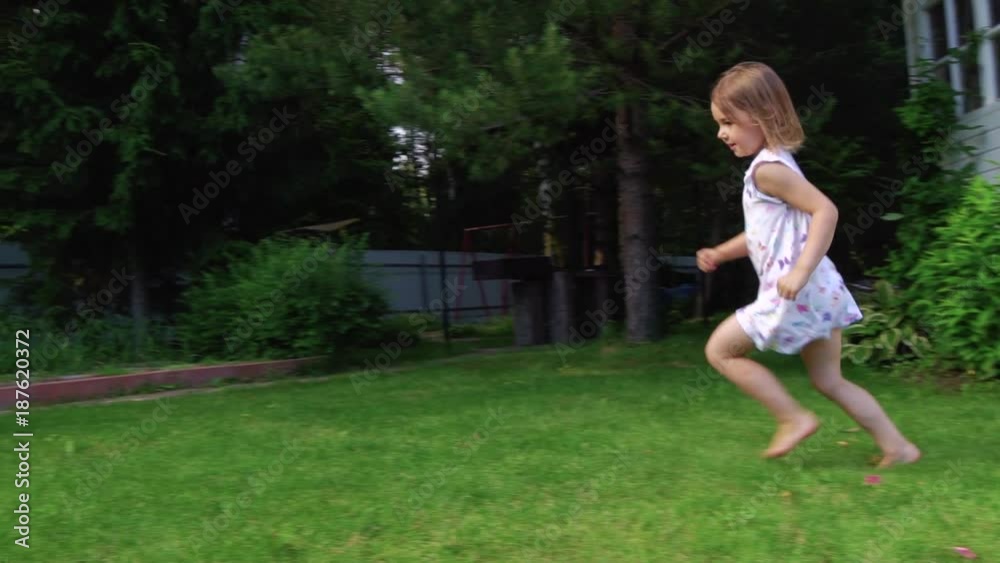 Happy 4-year-old girl running on meadow green grass in backyard. Slow Motion Happy 4-year-old girl running on meadow green grass in backyard. Slow Motion