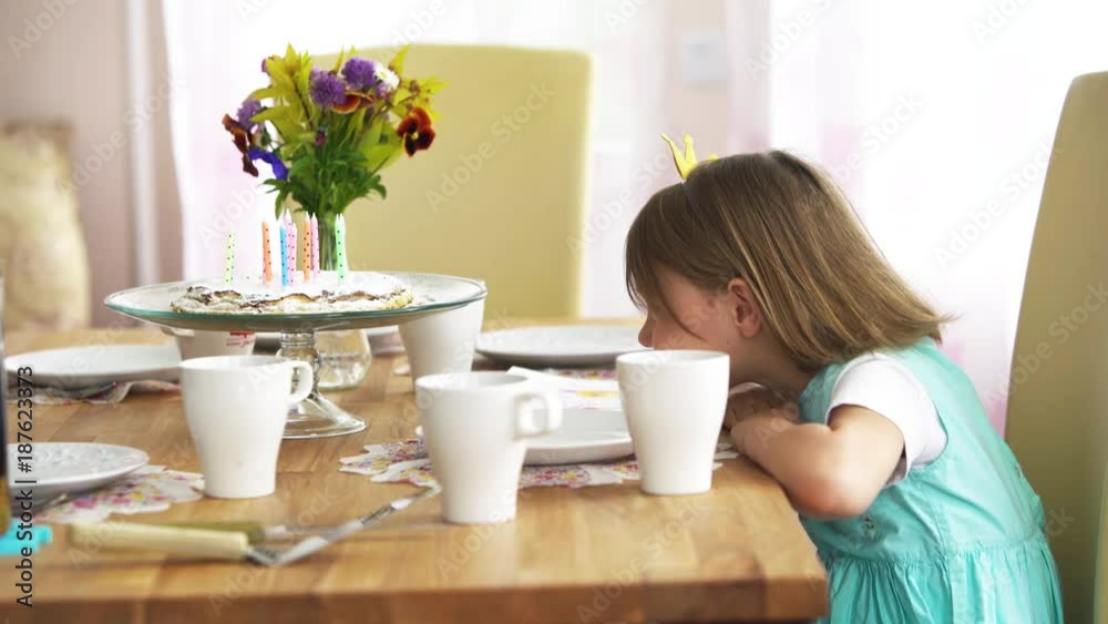 Little girl really wants to eat a festive homemade cake. She with pleasure licks finger with powdered sugar Little girl really wants to eat a festive homemade cake. She with pleasure licks finger with powdered sugar