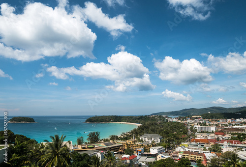 view of kata beach and kata city in phuket with boat traffic on the sea and clouds on bluie sky.