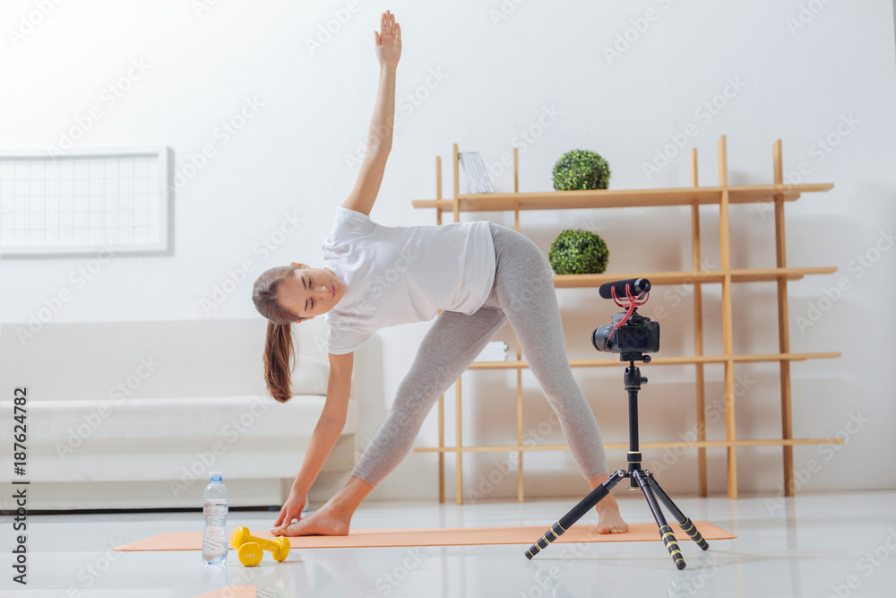 Lithe woman. Young yoga teacher doing asana in front of a modern camera and feeling relaxed while recording a video about it