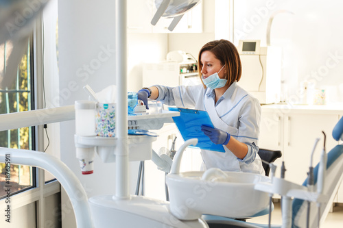 Female dentist in dental office .She cleans her equipment for next working day.