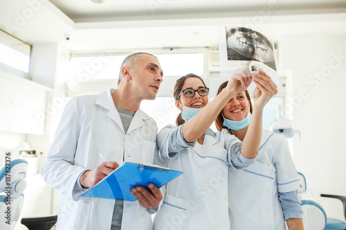 Принти на полотні Group of dentists examining x-ray image of patients teeth