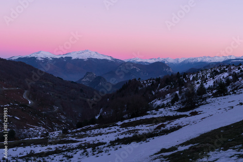 A pink sky after a sunset on mountains covered with snow in Pyrenees © Emilien