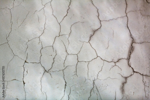 Textured surface of white wall with cracked plaster  