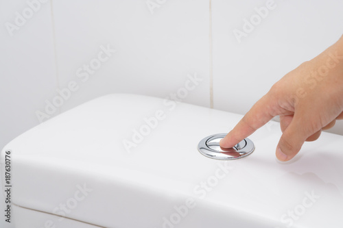 Close up of finger pushing a flush toilet button for cleaning. - save water concept