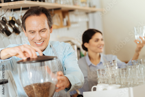 Fresh coffee. Interested responsible pleasant man standing in the kitchen smiling and making coffee.