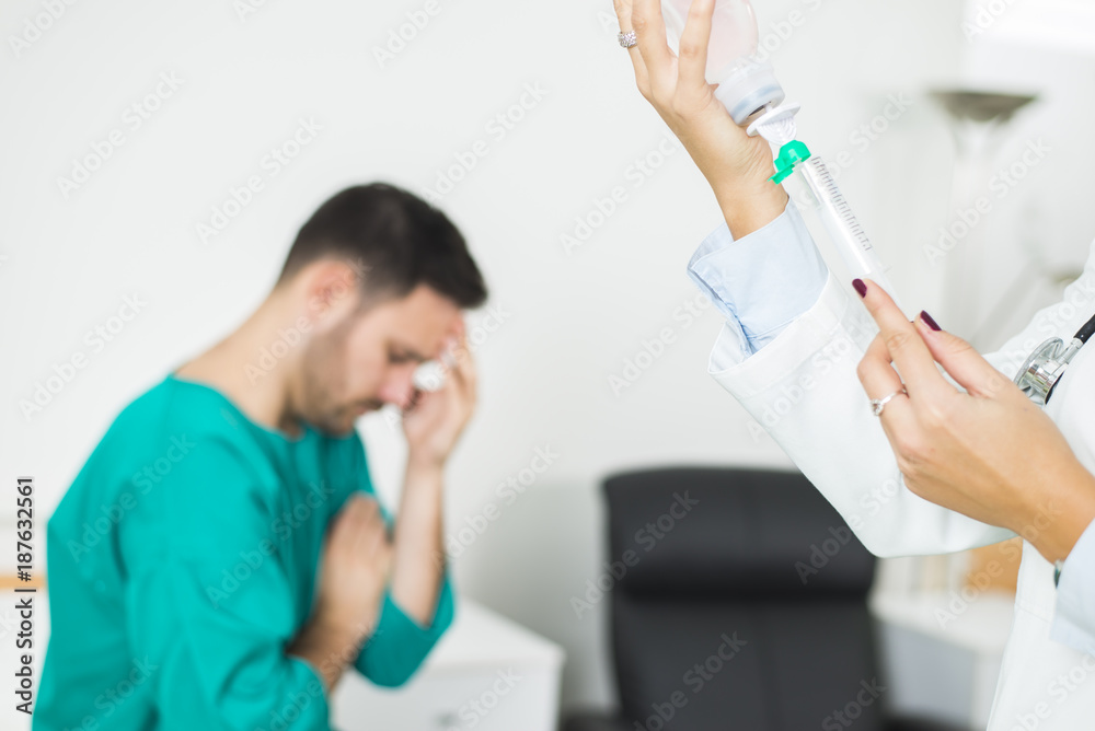 Female doctor prepares an injection while the patient is in bed Female doctor prepares an injection while the patient is in bed