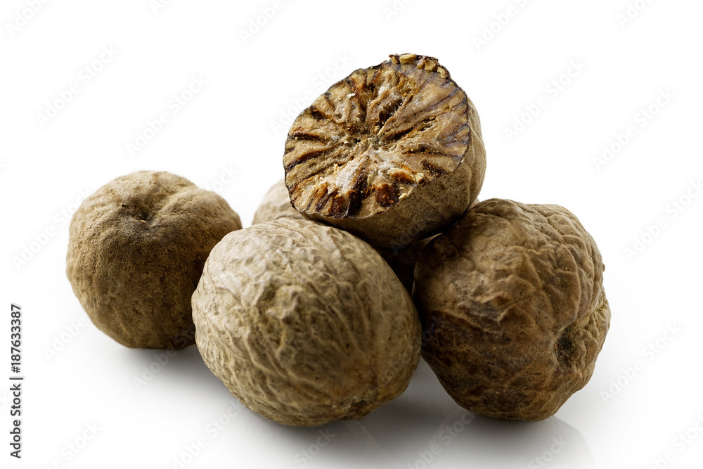 A pile of dried whole nutmegs isolated on white. A cut nutmeg. A pile of dried whole nutmegs isolated on white. A cut nutmeg.