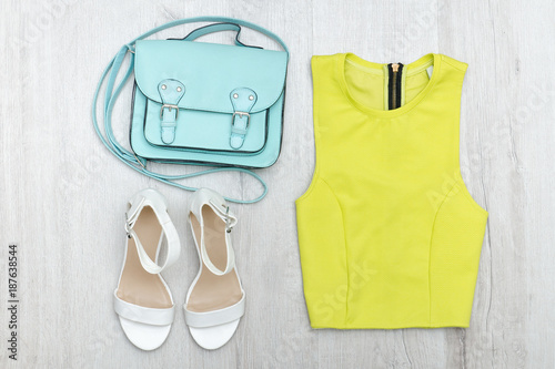 Lime green blouse, white sneakers and handbag. Fashionable concept. Wooden background.